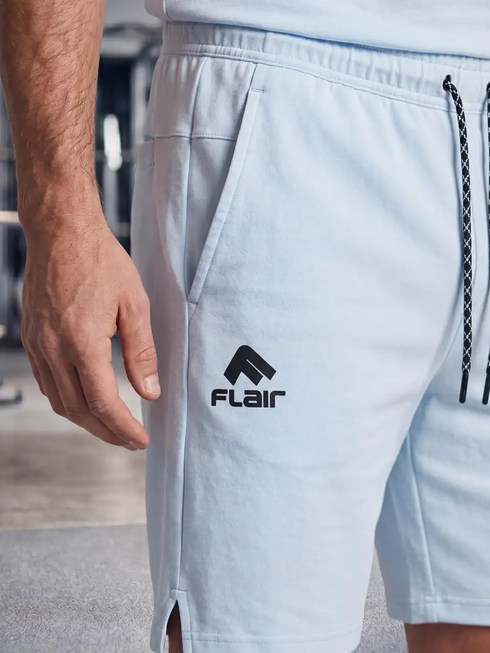 Prim-plan: logo-ul Flair și șireturile pantalonilor scurți