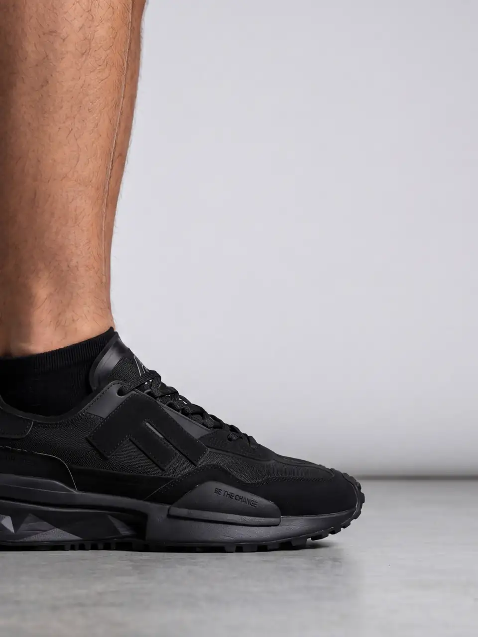Piciorul unui model într-un adidas negru Flair pe un fundal gri