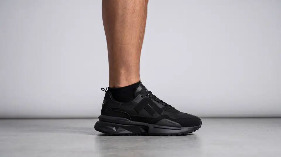 Model cu adidașii negri Flair pe un fundal gri de studio