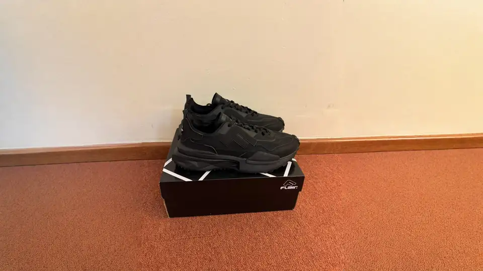 Black Flair sneakers on their box, shot on a phone