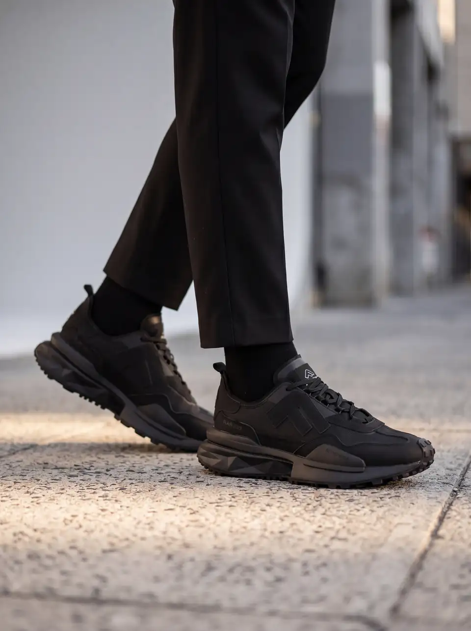 Model mergând pe stradă cu adidașii negri Flair